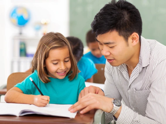 Elementary school teacher helping a student in class